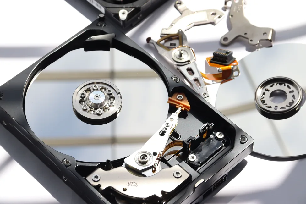 Disassembled hard drive parts including platters, actuator arms, and read/write heads